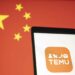 Temu logo on a cell phone against a backdrop of China's flag