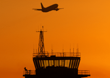 air traffic control tower with plane flying overhead