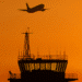 air traffic control tower with plane flying overhead