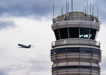 a plane takes off near an air traffic control tower
