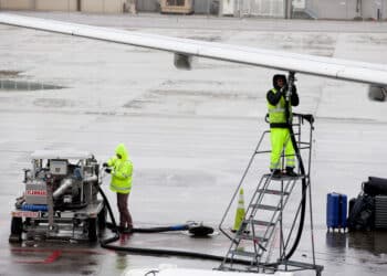 Ground operations employees fuel a plane on the tarmac at Denver International Airport. (Courtesy/Bloomberg)