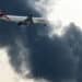 An Emirates aircraft prepares for landing as a smoke plume rises from an ongoing fire near Dubai International Airport on March 16. (Courtesy/Bloomberg)